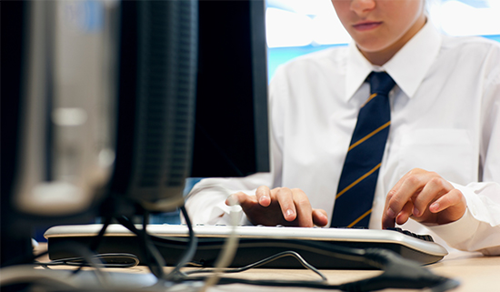 Image of a secondary school child in uniform using a keyboard