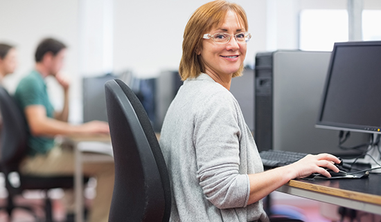 Image of a lady smiling at the camera sitting at her desk